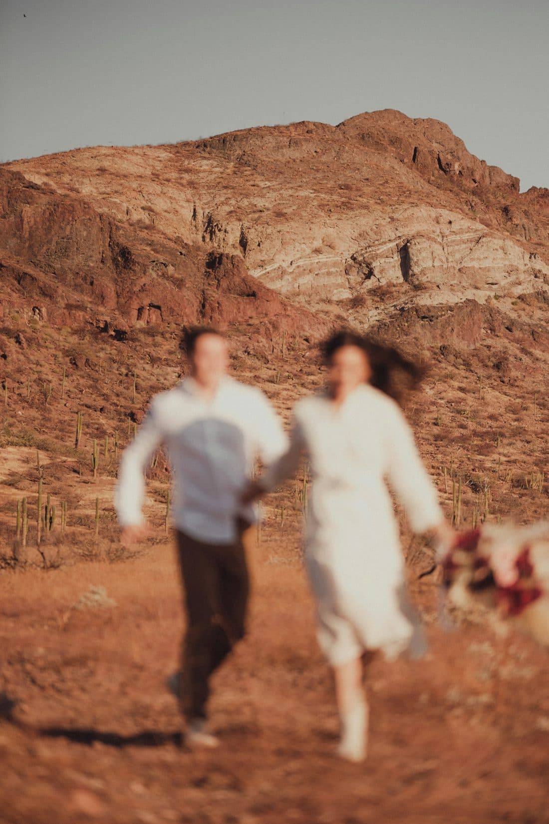 Couple running through a desert landscape