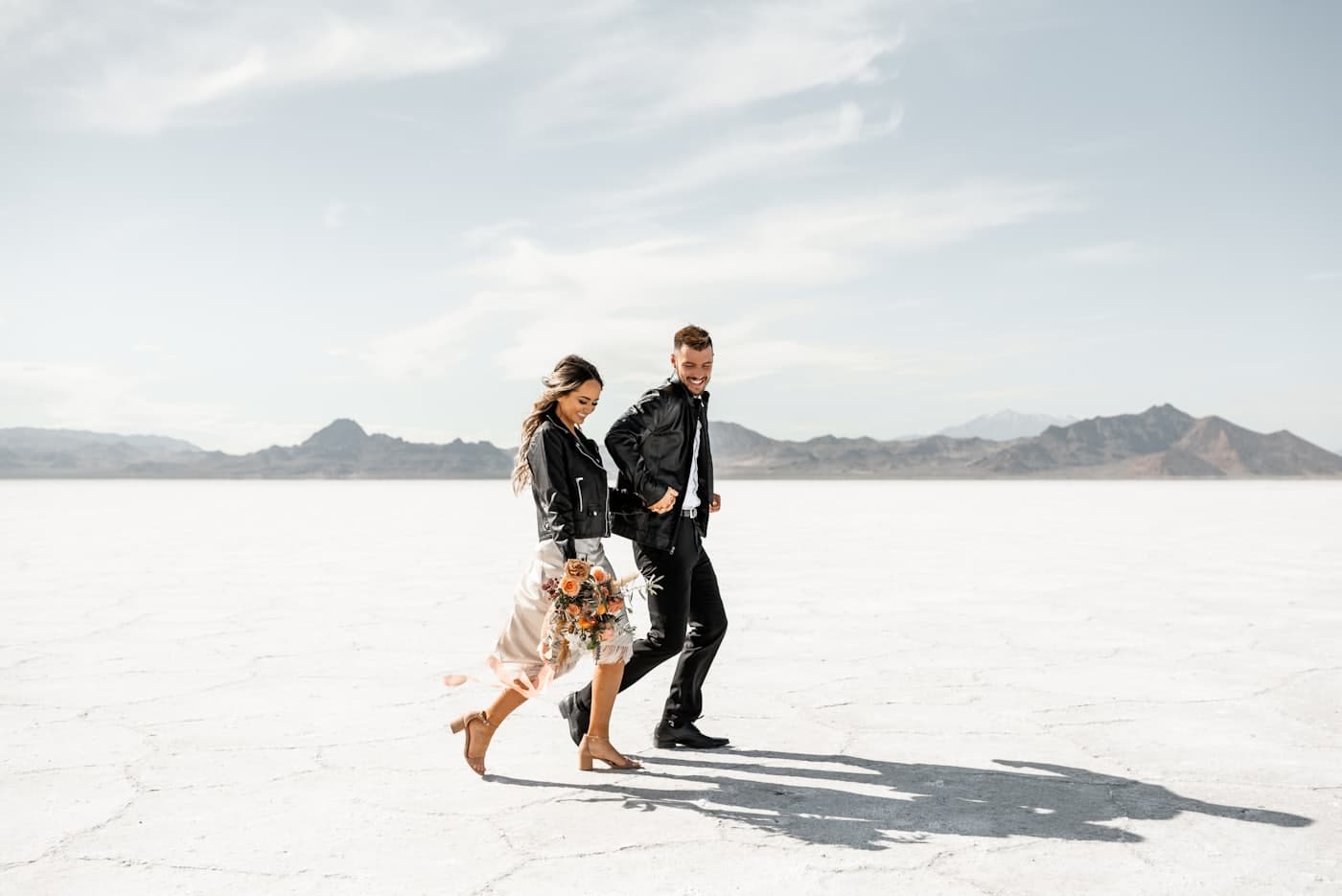 Couple walking across a vast, pale desert basin