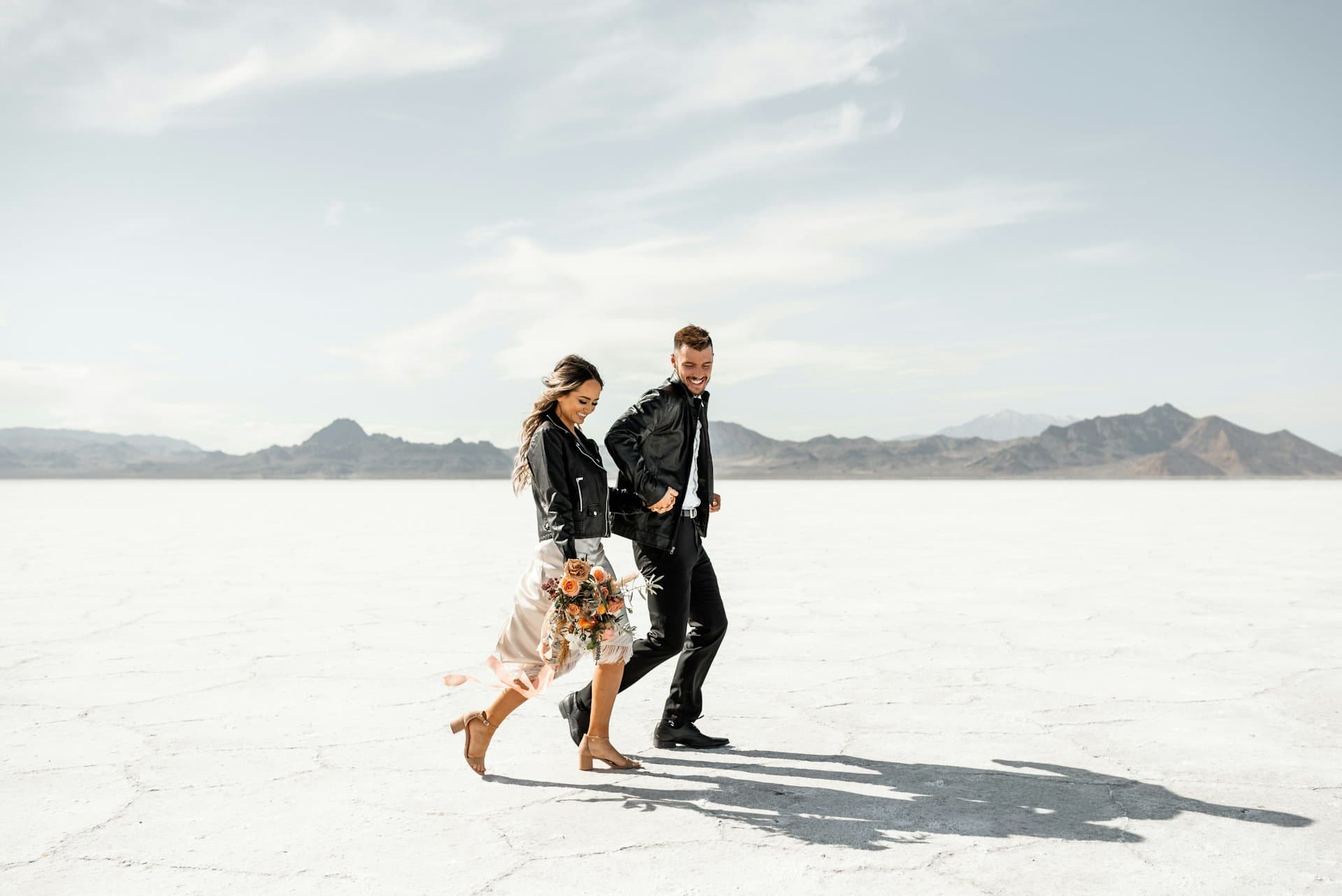 Couple walking across a vast, flat, white desert landscape.
