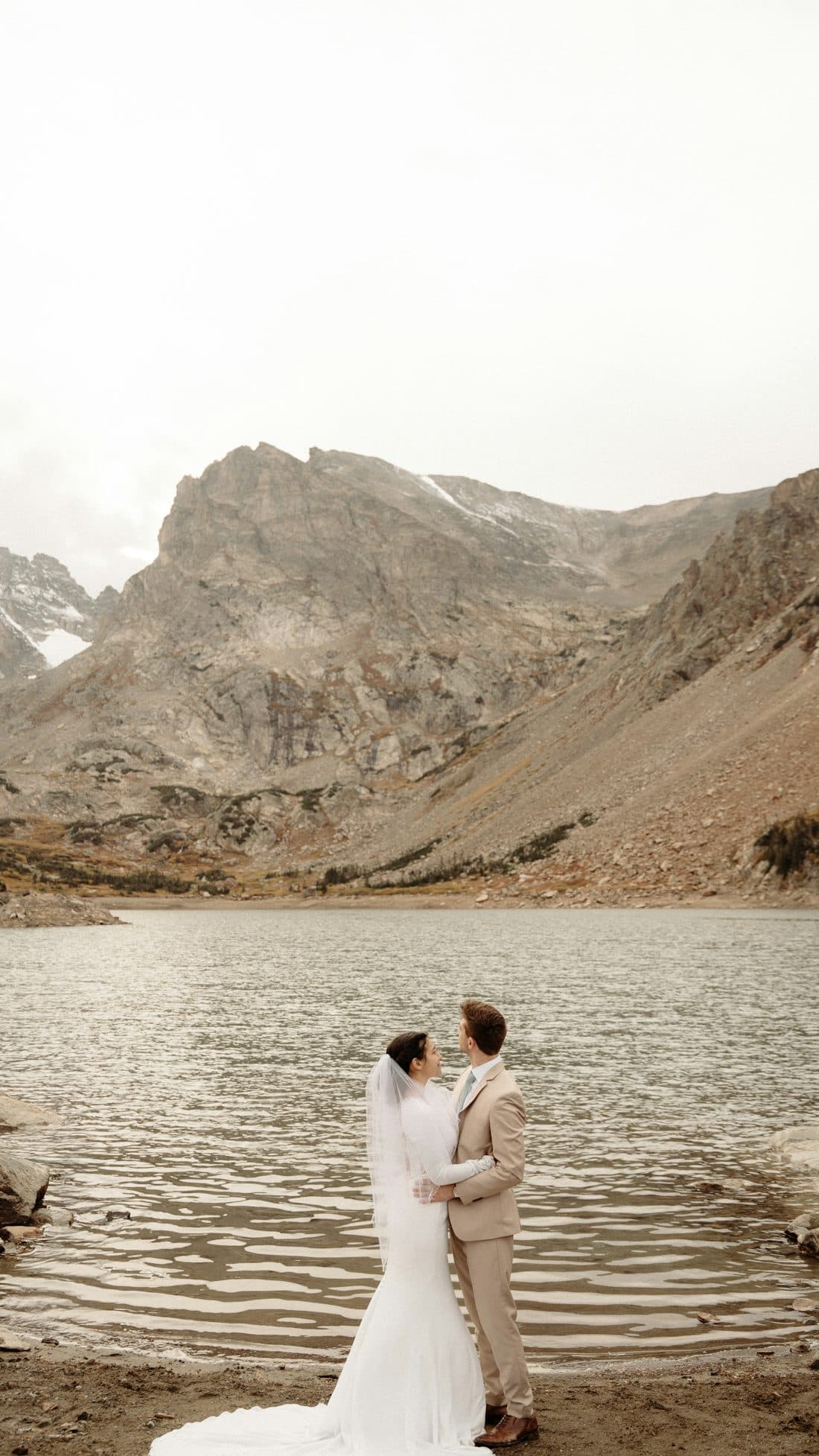 Couple standing before a mountain lake