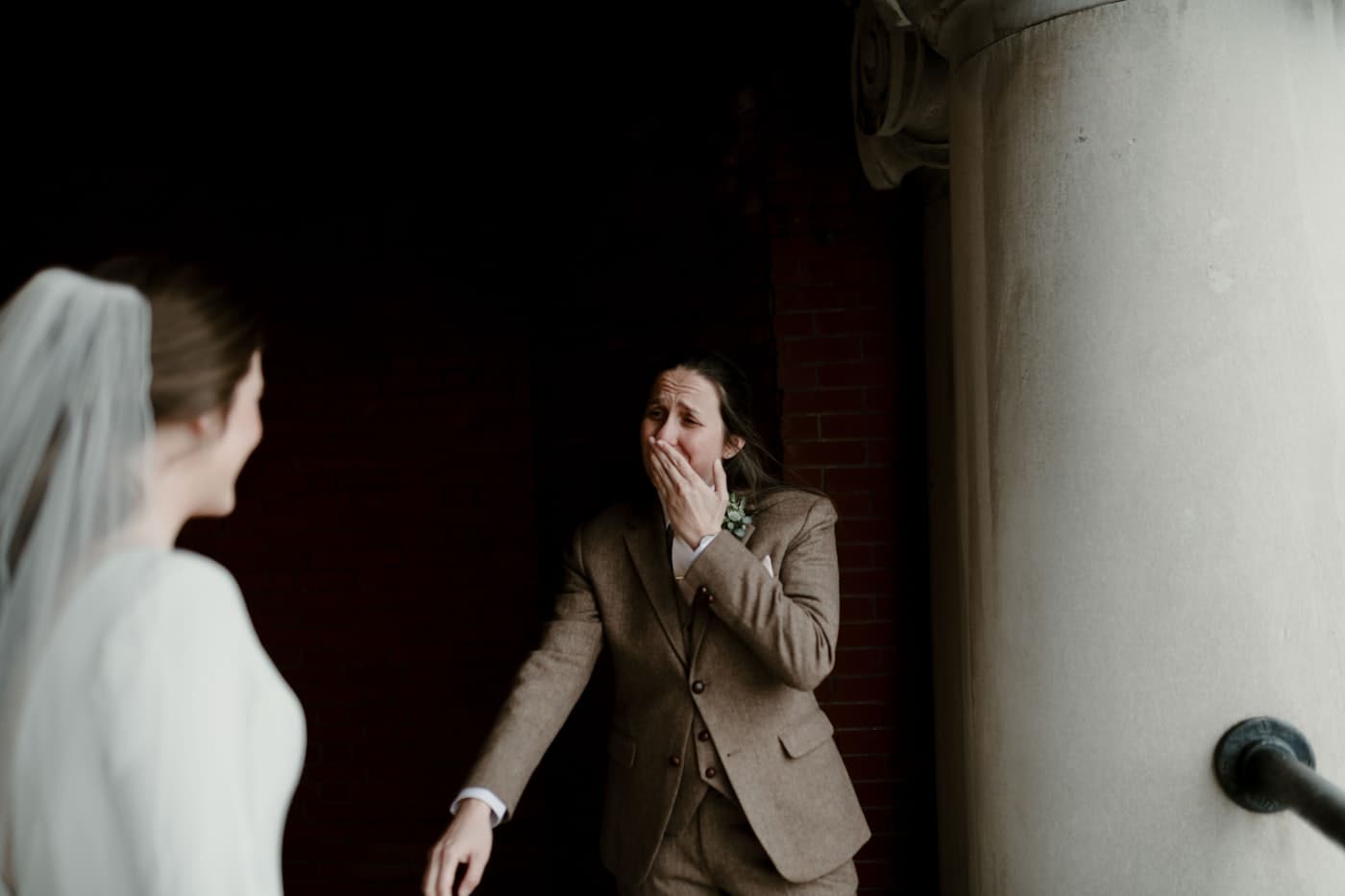 Groom in a brown coat beside the bride in white